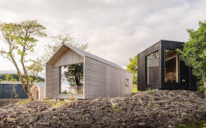 Des cabanes en bois à toit pointu s'intègrent aux reliefs écossais