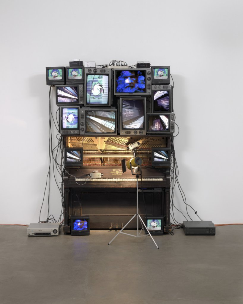 Installation artistique faite de plusieurs écrans de télévisions cathodiques installées sur un piano.